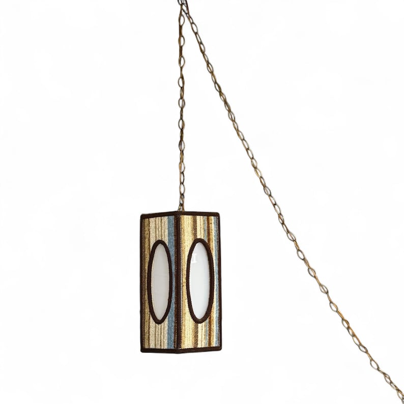 Vintage swag lamp with hexagonal shape and oval cutout, hanging on chain against a white background.