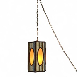 Vintage swag lamp with hexagonal shape and oval cutout, hanging on chain against a white background.