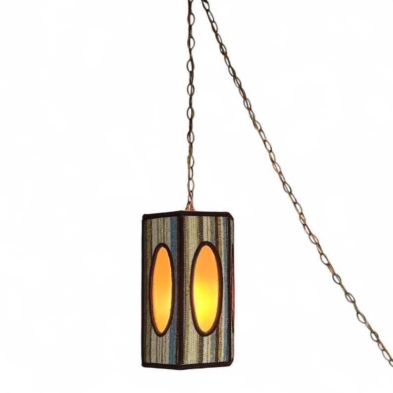 Vintage swag lamp with hexagonal shape and oval cutout, hanging on chain against a white background.