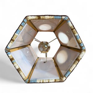 End view of a vintage swag lamp with hexagonal shape and oval cutout, hanging on chain against a white background.