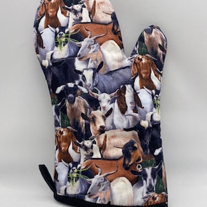 May include: A black and white oven mitt with a pattern of goats. The mitt is made of fabric and has a black hanging loop.