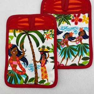 Può includere: Due presine rettangolari con bordo e tasca superiore rossi. Le presine presentano uno sfondo bianco con una stampa tropicale di ballerine di hula, palme e fiori. La tasca superiore ha un design a righe arancioni e rosse.