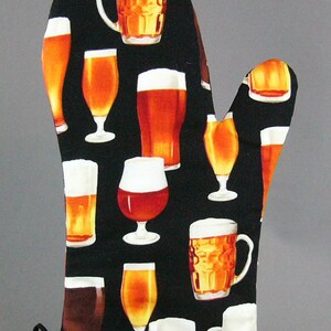 May include: Black oven mitt with a pattern of various beer glasses and mugs. The glasses are filled with a light amber colored liquid.