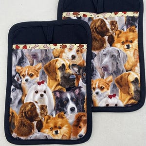May include: Two rectangular pot holders with black fabric trim and a hanging loop. The center features a colorful collage of various dog breeds, including a white dog with a red bow, a brown spaniel, and a black and white dog, accented by a top border of paw prints.
