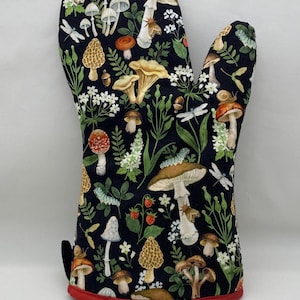 May include: Black oven mitt with a red trim. The mitt is covered in a pattern of mushrooms, leaves, and flowers.