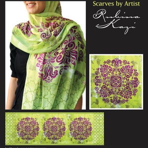May include: A light green scarf with a repeating purple floral pattern. The scarf is draped around a person's neck and shoulders. The image also includes a close-up of the scarf's design and the text "Scarves by Artist Rubina Kazi."