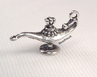 May include: A small, silver-coloured genie lamp charm with a curved spout, a round base, and a loop at the top. The lamp has intricate detailing and is set against a white background. The text "BeadVault" is visible on the side.