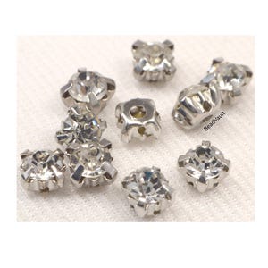 May include: Assortment of clear crystal rhinestones with silver settings. The rhinestones are in various sizes and shapes, and they are perfect for adding sparkle to crafts and jewelry.
