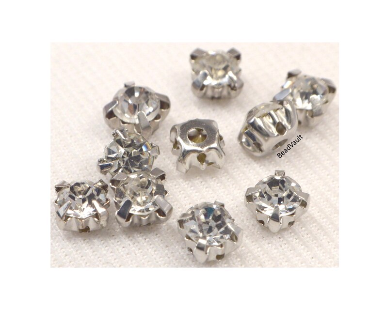 May include: Assortment of clear crystal rhinestones with silver settings. The rhinestones are in various sizes and shapes, and they are perfect for adding sparkle to crafts and jewelry.