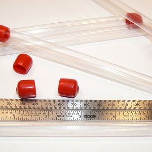 May include: Five clear plastic tubes with red caps. The tubes are approximately 15 inches long. A metal ruler is placed next to the tubes for scale.