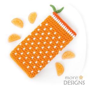 May include: An orange crocheted phone case with white polka dots, a green stem, and an orange trim. The case is surrounded by orange candy slices. The design is reminiscent of a tangerine.