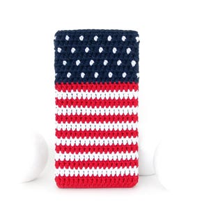 May include: A rectangular crochet phone sleeve featuring a dark blue top section with white polka dots and a lower section with alternating horizontal red and white stripes. The textile accessory has a dense, textured yarn construction.
