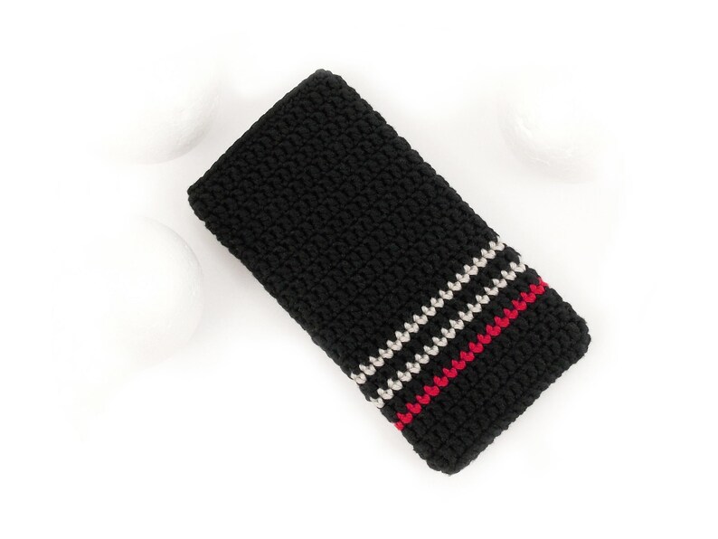 Puede incluir: Funda de tel&eacute;fono de crochet negro con rayas blancas y rojas.