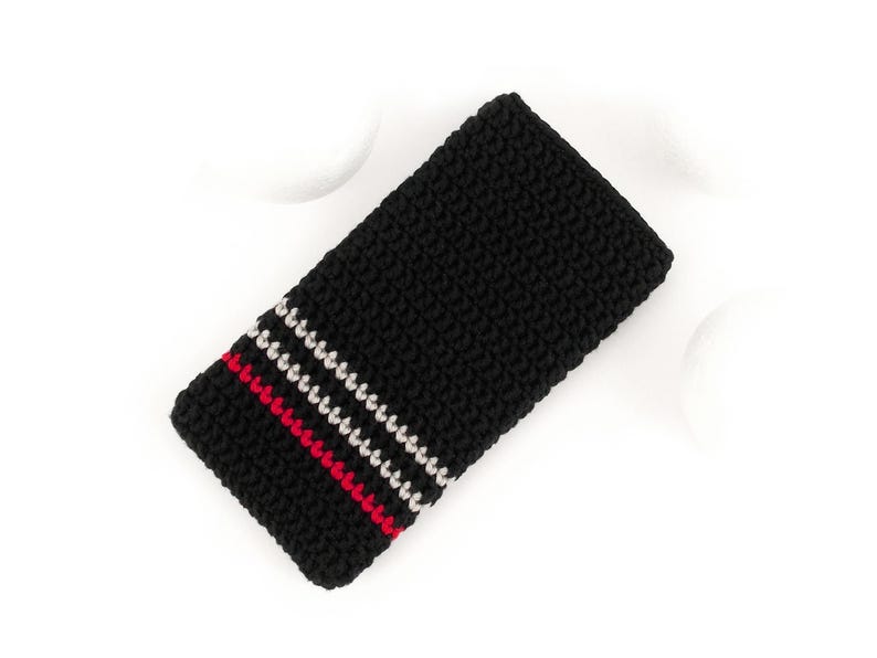 Puede incluir: Funda de tel&eacute;fono de crochet negro con rayas rojas y blancas.
