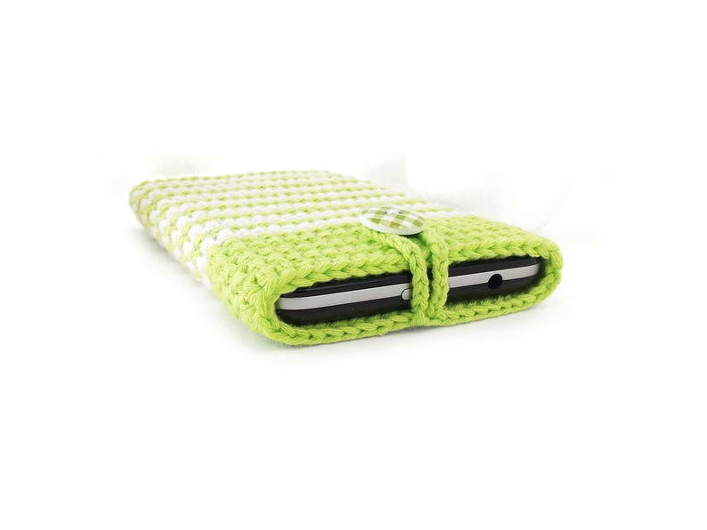 Puede incluir: Una funda rectangular para tel&eacute;fono hecha de hilo de ganchillo en color verde lima y blanco. La funda presenta un patr&oacute;n de punto texturizado y un cierre de bot&oacute;n de tela de cuadros vichy verde lima y blanco que asegura el dispositivo.