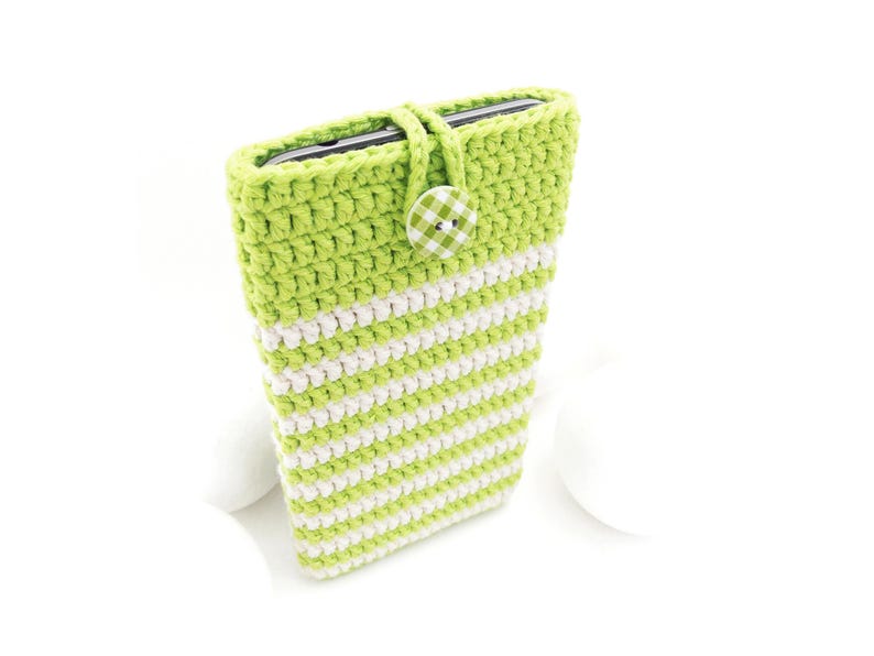 Puede incluir: Una funda de ganchillo para tel&eacute;fono a rayas verde lima y blancas, con una secci&oacute;n superior en verde lima s&oacute;lido, un cierre de bucle de ganchillo a juego y un bot&oacute;n redondo con estampado de cuadros vichy verde lima y blanco.