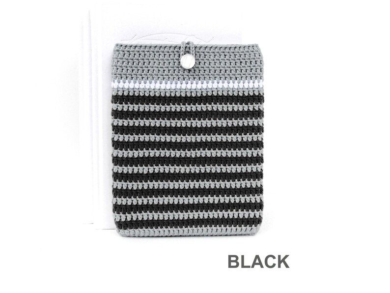 Crocheted e-reader soft case made of Grey durable cotton yarn with Black stripes and White stripe above them. The e-reader cover closes with a White plastic button and a strong loop.
