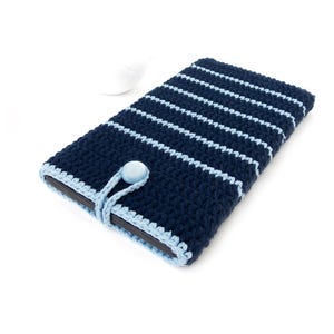 Puede incluir: Una funda para tablet de crochet a rayas azul y azul claro con cierre de botón.
