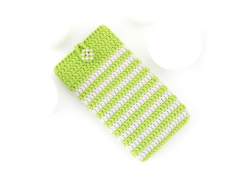Puede incluir: Una funda rectangular de ganchillo con rayas horizontales en verde lima y blanco. La funda se asegura en la parte superior con un peque&ntilde;o bot&oacute;n redondo de estampado de cuadros vichy verde y blanco unido a una trabilla de ganchillo.