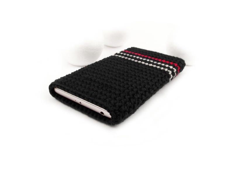 Puede incluir: Funda de tel&eacute;fono de crochet negro con rayas rojas y blancas.