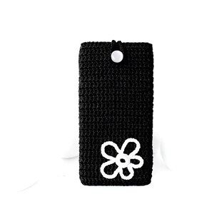 Op de afbeelding: Zwarte gehaakte telefoonhoes met een wit gehaakt bloemenmotief.