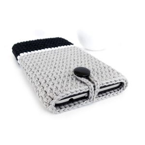 May include: Grey, black and white crocheted phone case with a black button closure.
