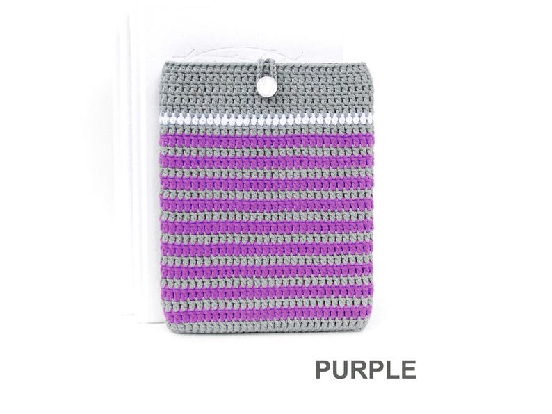 Crocheted e-reader soft case made of Grey durable cotton yarn with Purple stripes and White stripe above them. The e-reader cover closes with a White plastic button and a strong loop.