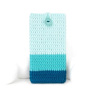 Puede incluir: Una funda de teléfono de ganchillo hecha a mano en tonos azules. La funda presenta un cierre de botón y un diseño a rayas, con un degradado de azul claro a azul oscuro. La funda es rectangular y parece estar hecha de hilo suave.