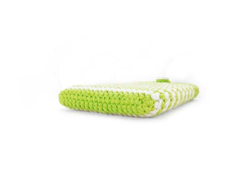 Puede incluir: Un estuche rectangular elaborado con hilo verde lima y blanco en un patr&oacute;n de punto de ganchillo denso. El art&iacute;culo presenta una construcci&oacute;n gruesa y texturizada con un cierre de bot&oacute;n blanco visible en el borde superior del tejido plano.