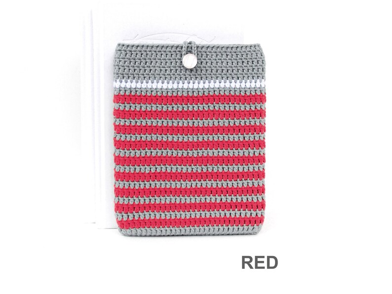 Crocheted e-reader soft case made of Grey durable cotton yarn with Red stripes and White stripe above them. The e-reader cover closes with a White plastic button and a strong loop.