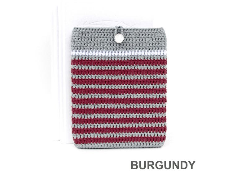 Crocheted e-reader soft case made of Grey durable cotton yarn with Burgundy stripes and White stripe above them. The e-reader cover closes with a White plastic button and a strong loop.