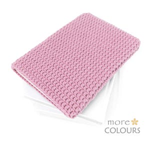 Può includere: Un oggetto rettangolare all'uncinetto rosa chiaro, possibilmente una custodia o un astuccio. L'oggetto ha una superficie strutturata ed è posto su uno sfondo bianco. Le parole "more COLOURS" sono visibili nell'angolo in basso a destra.