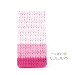 May include: A crocheted blanket with three horizontal stripes in shades of pink, light pink, and white. The blanket is made with a simple stitch pattern.