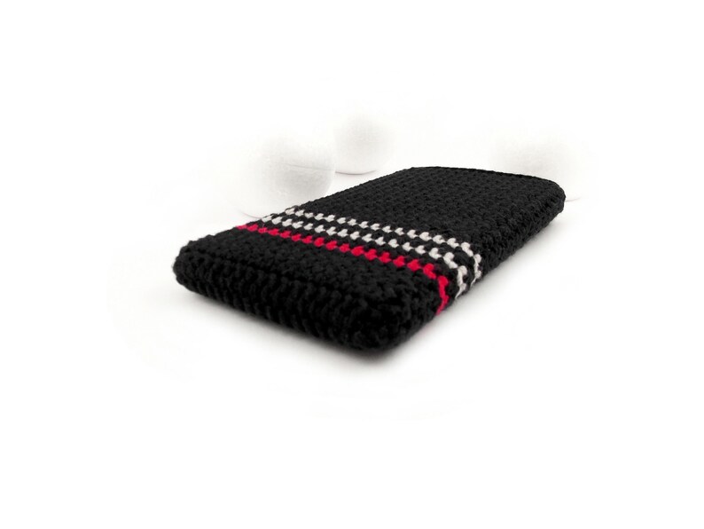 Puede incluir: Funda de tel&eacute;fono de crochet negro con rayas rojas y blancas.