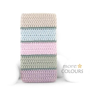 May include: A rectangular, crocheted item with horizontal stripes in pastel shades of beige, light blue, pink, and green. The item is displayed on a white background with the text "more COLOURS".