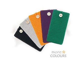 Puede incluir: Cinco fundas rectangulares de ganchillo en negro, gris claro, naranja, morado y verde. Cada funda cuenta con un botón de madera de color claro en la parte superior central. El texto "more COLOURS" con un pequeño icono de flor es visible.