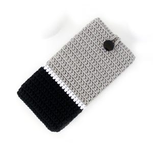 May include: Grey, black and white crocheted phone case with a black button closure.