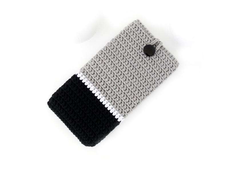 May include: Grey, black and white crocheted phone case with a black button closure.