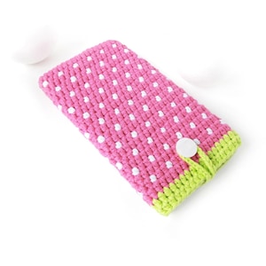 Könnte beinhalten: Rosa-weiß gepunkteter Handy-Etui aus Häkelarbeit mit grünem Besatz und einem weißen Knopf.