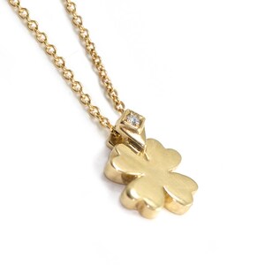 May include: A gold necklace with a four-leaf clover pendant featuring a small diamond in the center.