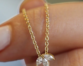 May include: A delicate gold chain necklace with a pendant featuring three marquise-shaped diamonds set in a cluster.