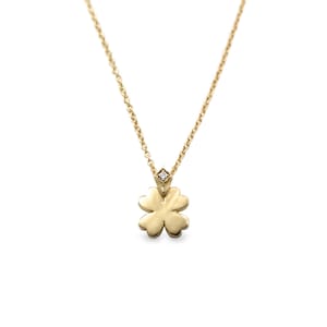 May include: A gold necklace with a four-leaf clover pendant and a small diamond accent.