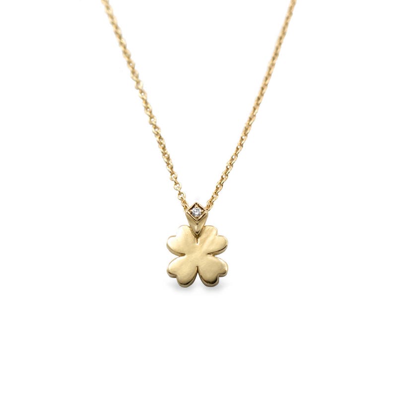 May include: A gold necklace with a four-leaf clover pendant and a small diamond accent.
