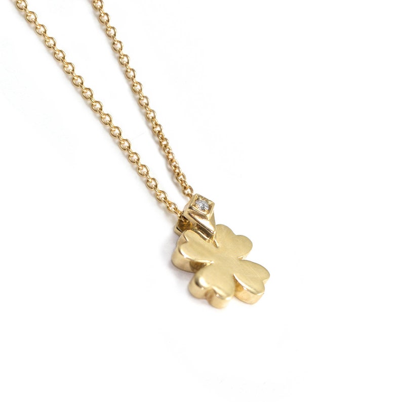 May include: A gold necklace with a four-leaf clover pendant featuring a small diamond in the center.