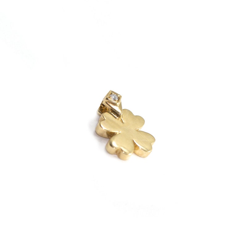 May include: A gold four-leaf clover charm with a single diamond in the center.