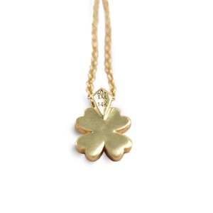May include: A gold four-leaf clover pendant necklace with a 14K hallmark. The pendant is attached to a delicate gold chain.