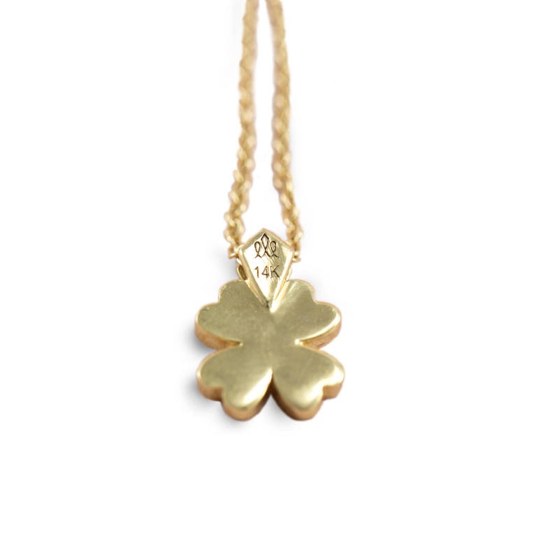 May include: A gold four-leaf clover pendant necklace with a 14K hallmark. The pendant is attached to a delicate gold chain.