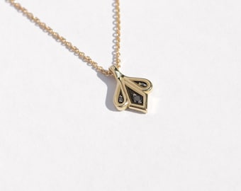 Op de afbeelding: Een gouden ketting met een hanger in de vorm van een gestileerde bloem met drie zwarte diamanten in het midden.