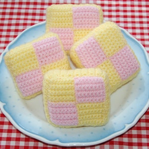 Può includere: Quattro quadrati all'uncinetto in giallo e rosa su un piatto blu e bianco. I quadrati sono impilati, con il quadrato superiore leggermente spostato.