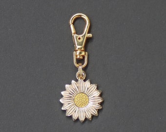 May include: Gold-colored keychain with a sunflower charm. The charm features a detailed sunflower design with a yellow center and cream-colored petals. The keychain has a lobster clasp for easy attachment.